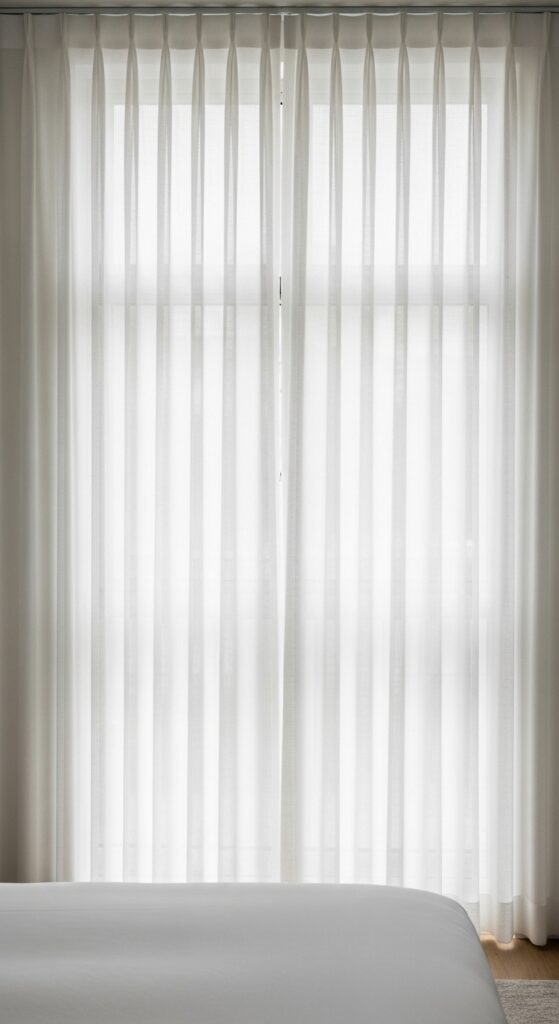 Bedroom with floor-to-ceiling white curtains creating height and elegance