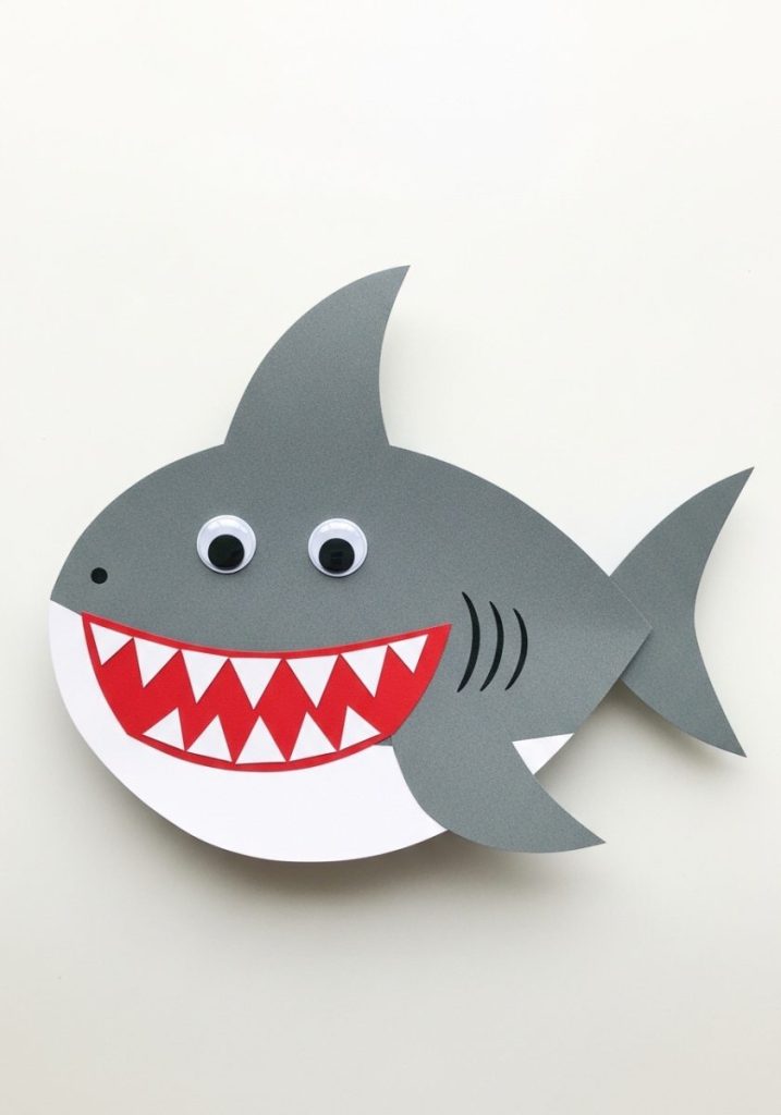 Construction paper shark craft kids grey construction paper assembled shark shape white paper belly red mouth white teeth googly eyes grey fin playful creative achievable basic craft supplies