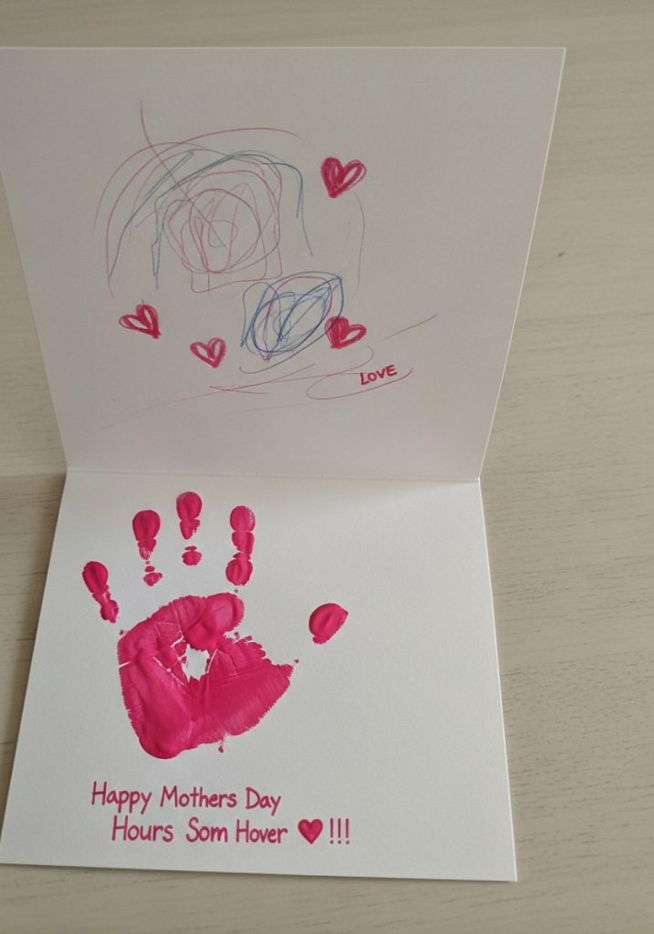 Preschool mothers day handprint card small child handprint bright pink paint white folded card simple message inside scribbled drawing love hearts adorable precious heartfelt