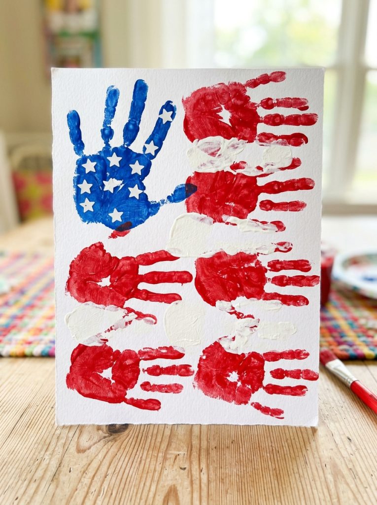 Beautiful american flag handprint july craft with red white striped handprints and blue section with star stickers on white paper