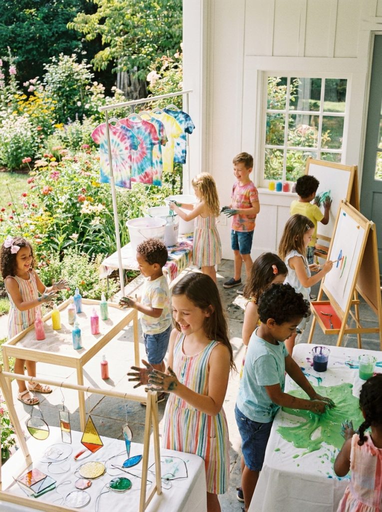 Complete fun summer craft day with multiple stations for tie dye sand art sun catchers slime and painting with excited children