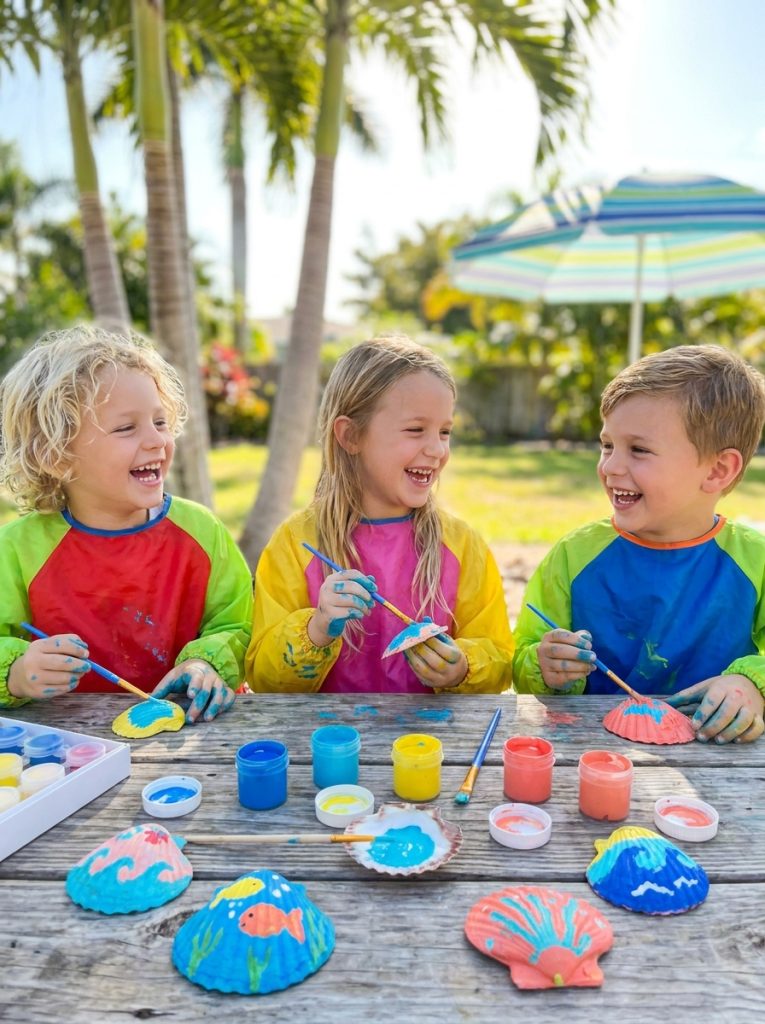 Kids using seashell paint kit creating cheerful ocean-inspired seashell art with bright summer colors on summer craft table
