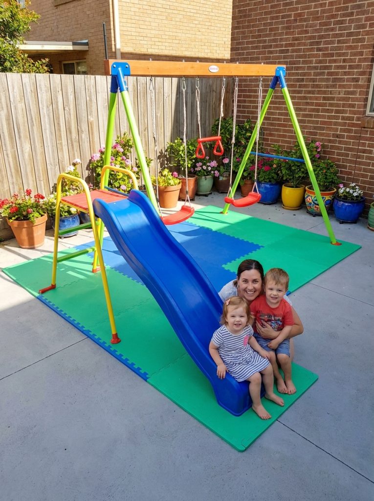 DIY kids playground on concrete paved backyard with rubber mat and colorful swing set