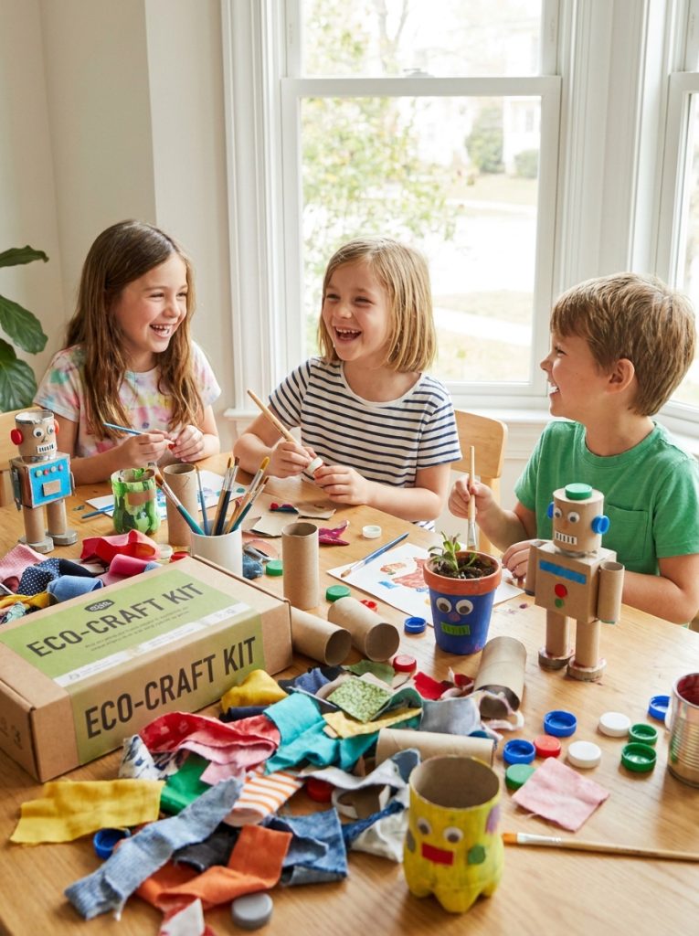 Kids working on upcycling craft project with colorful eco friendly supplies on bright craft table
