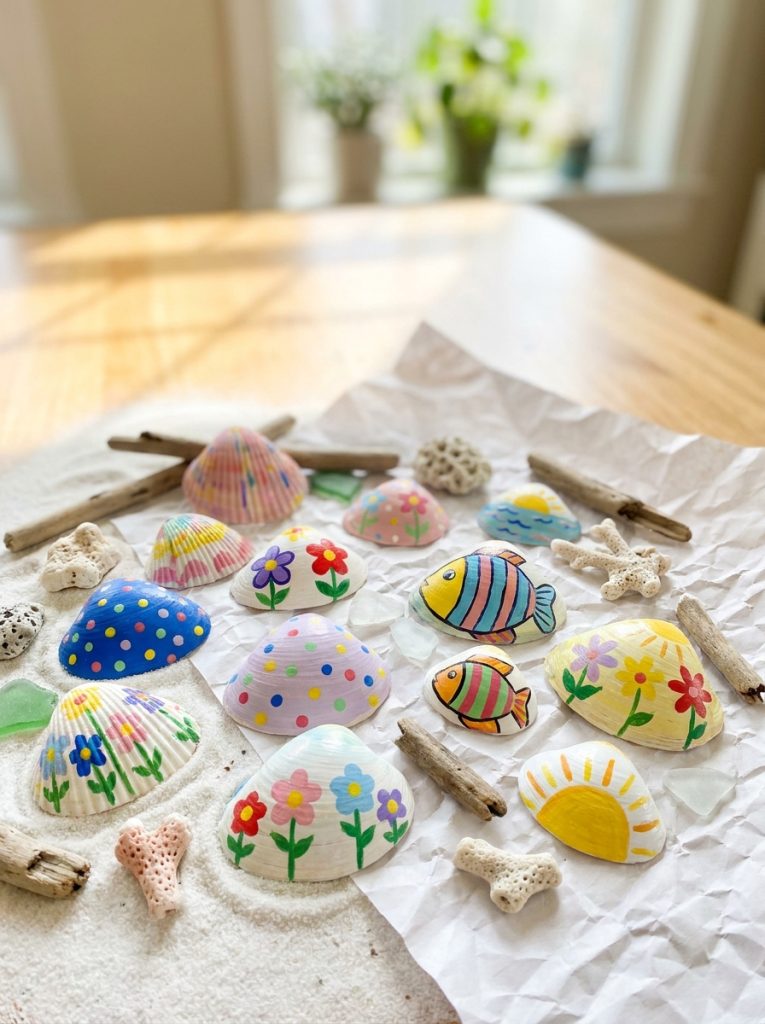Adorable painted seashell crafts made by kids with shells painted in bright colors with dots flowers and ocean designs displayed