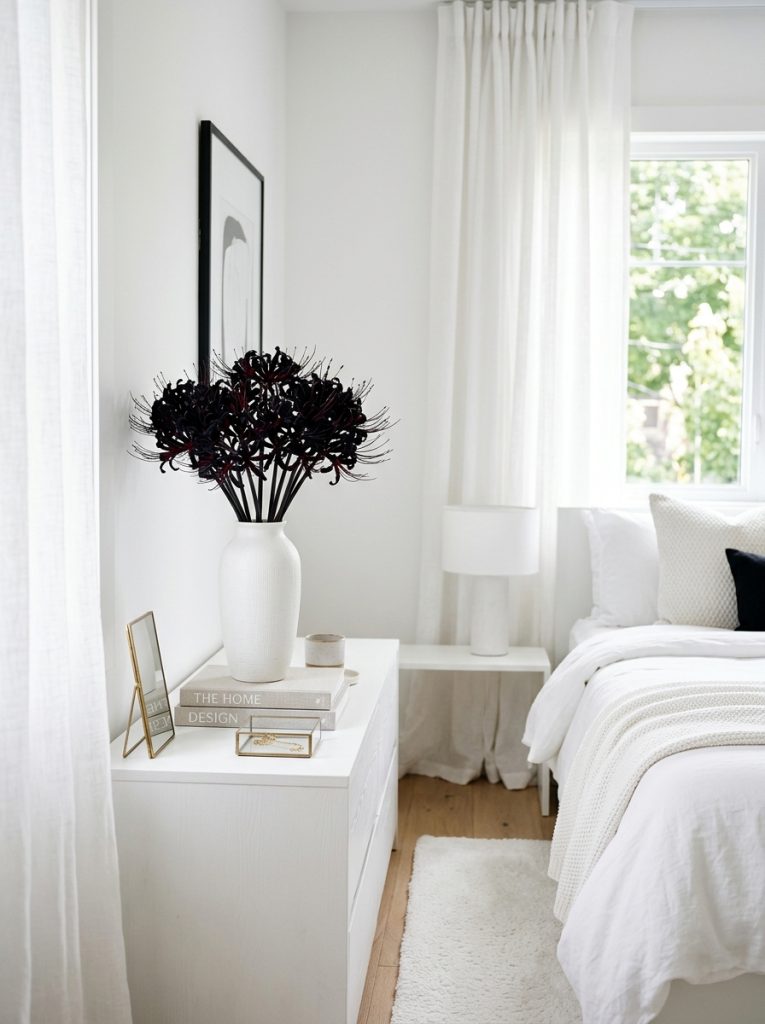 Strikingly dramatic bedroom with black spider lilies tall white ceramic vase deep midnight petals white dresser and walls