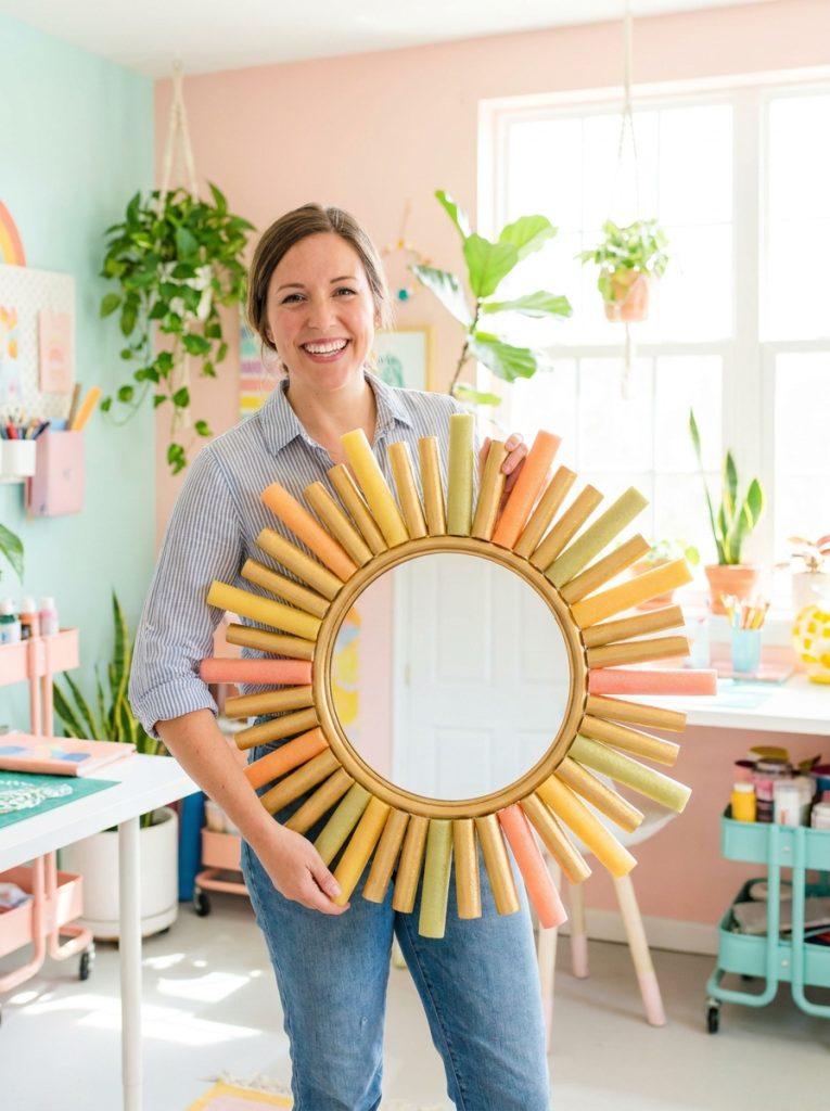 Creative DIY mirror frame made from pool noodles cut in sunburst pattern around round mirror painted gold