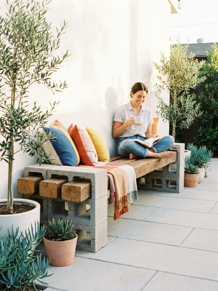 Modern DIY outdoor bench with concrete block stacks and thick wooden planks on clean bright patio
