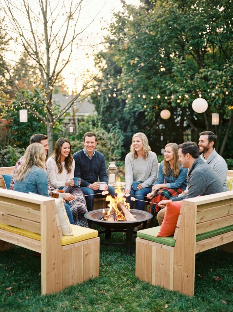DIY wooden benches arranged in semicircle around outdoor fire pit warm evening outdoor setting